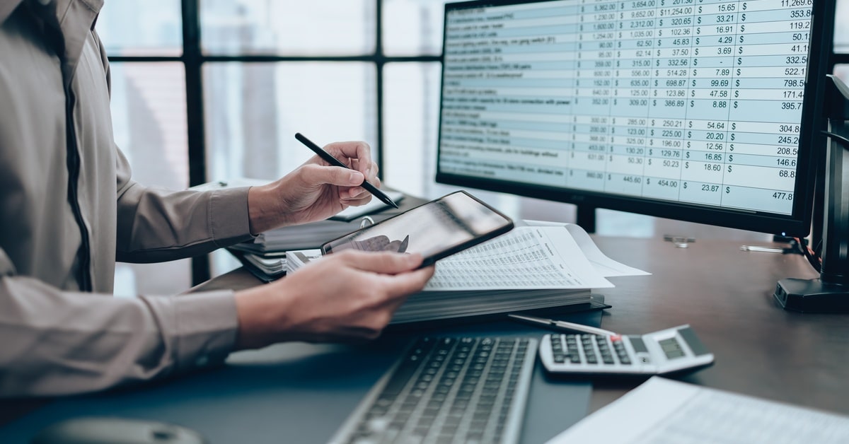 A sewage truck is parked on a tree-lined road. A red hose leads from the back of the truck to the side of the road.