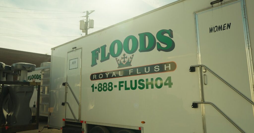 The outside wall of a luxury porta potty with doors for men and women. The exterior reads "Floods Royal Flush."