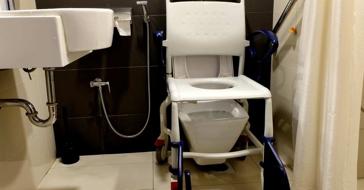 A mobile toilet seat placed over top of a toilet for use by handicapped individuals. A small sink is near the toilet as well.