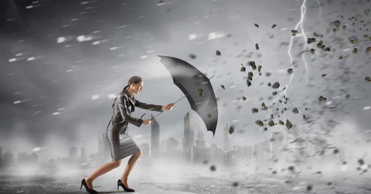 A businesswoman braces with an umbrella against high winds as rain, debris, and lightning surge around a city skyline.